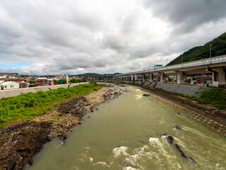 濁った水が流れる雨上がりの猪名川と街の風景