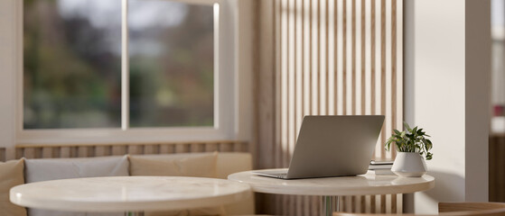 A back view image of a laptop computer on a table in a modern, comfortable cafe seating area.