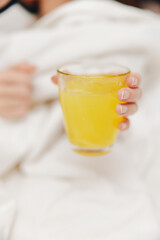 Person laying in bed with a glass of orange juice in front of them