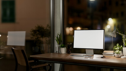 Contemporary private office at night features a computer with a white-screen mockup and a dim light.