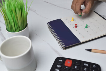 View of hand use pushpin on calendar to booking about date and time of meeting for day off vacation