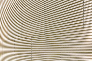 textured beige stone wall with horizontal ridges and stripes. architectural background.