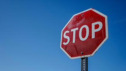 Obraz premium Red and white stop sign on the side of the road isolated on a blue sky background.
