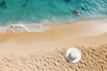 Obraz premium Overhead View of a Sandy Beach with Turquoise Water and a White Sun Hat