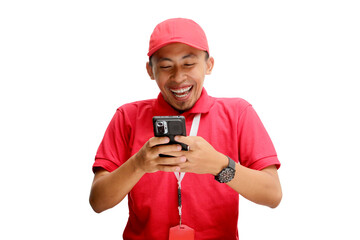 Enthusiastic Asian delivery man or courier joyfully reading great news on his smartphone, expressing excitement and happiness. Isolated on a white background