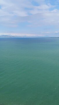 Top view blue lake Sevan waves break on sand beach. Taken with a drone.