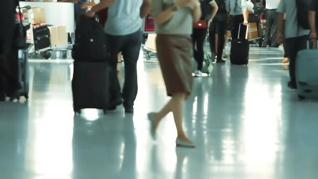 Selective focus on travelers at a busy airport waiting to check in and board. Passengers handle luggage, check flight info, and prepare travel documents amid the bustling scene