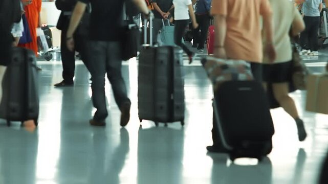 Selective focus on travelers at a busy airport waiting to check in and board. Passengers handle luggage, check flight info, and prepare travel documents amid the bustling scene