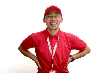 Confident Asian delivery man or courier stands with his hand on his hip in an arm akimbo gesture, isolated on white background. Concept of reliability, trustworthiness, logistics and delivery services
