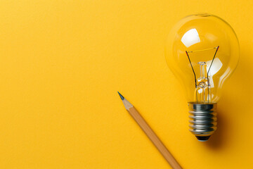 Business creativity and inspiration with a lightbulb and pencil on a yellow background