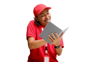 Excited Asian delivery man or courier having an engaging phone call with a customer while taking notes on a notebook. Isolated on a white background