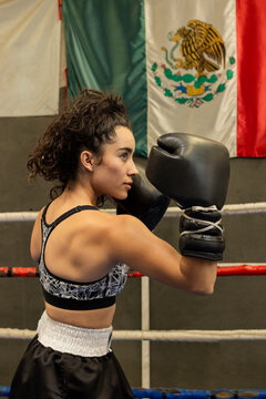 portrait of a strong latina boxer in the ring in a gym, Mexican boxer fighting with the flag of Mexico in the background
