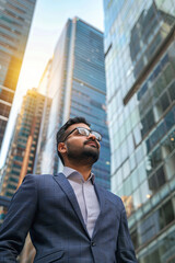 Confident Eastern Indian businessman in a modern city, visualizing future business success and setting new goals