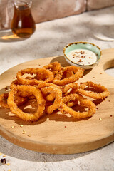 Sunlit Tempura Squid Rings with Tartar Sauce on Wooden Board Still Life