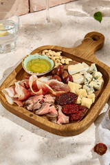 Summer Cheese and Meat Platter with Sun-Dried Tomatoes and Olives in Sunlight and Shadow
