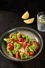 Fresh and Vibrant Shrimp and Strawberry Salad in Bowl with Lemon and Water on Dark Background