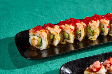 Delicious Salmon and Shrimp Sushi Roll with Tobiko Caviar on Black Plate