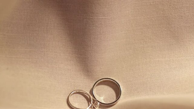 Dropping a pair of engagement rings made of platinum and diamonds on a cloth laid on a table.