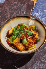 Sweet and Sour Chinese-Style Chicken with Vegetables and Cilantro in a Rustic Bowl