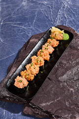 Gourmet Spicy Sushi Set on Black Slate Platter with Ocean Blue Background