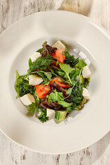 Greek Salad in White Plate Amid Summer Still Life Fresh, Sunlit, Wooden Background