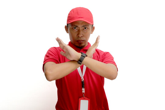 Asian delivery man or courier crosses his arms in a stop or refuse gesture, isolated on white background. Concepts of limitations, restrictions, refusal of service, and boundaries in delivery services
