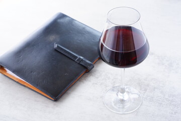 赤ワインを飲みながら、黒い革のシステム手帳に日記をつけているイメージ
