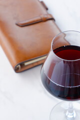 赤ワインを飲みながら、茶色の革のシステム手帳に日記をつけているイメージ
