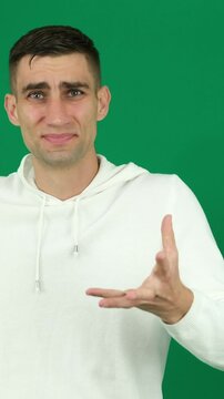 Disgust man. emotions of a handsome man guy on a green background chromakey close-up dark hair young man Young hispanic man standing, wearing shirt