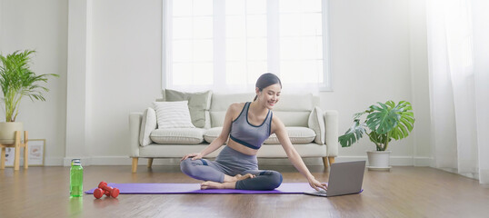 Fototapeta premium Portrait of beautiful asian korean woman stretch warm up exercise workout yoga position with laptop at home living room. Sport asian girl health care lifestyle. Yoga for beginner wellbeing banner