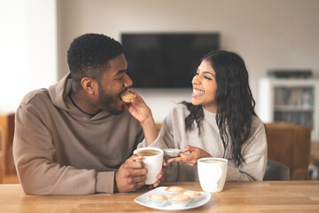 Happy Couple Enjoying Coffee and Pastries Together in Their Living Room
