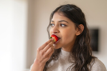 Young Woman Eating Strawberry Indoors