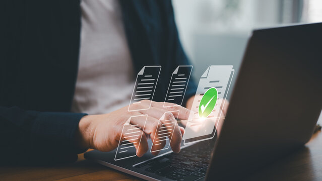 Document management concept. Person using laptop computer with finger pointing to green check mark and document for online document approve in paperless and business process workflow.