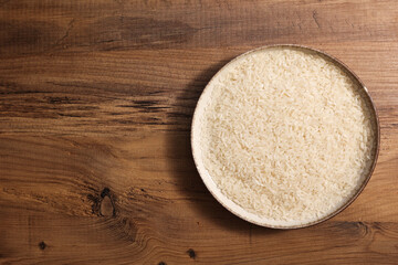 Close-up of a bowl filled with rice placed on a rustic wooden table, emphasizing the details of the rice grains.