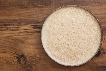 A bowl filled with rice on a wooden table, highlighting the natural texture and simplicity of the grain.