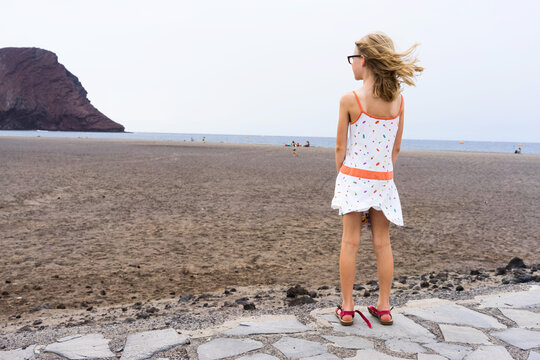 Girl standing looking out to the beach and sea