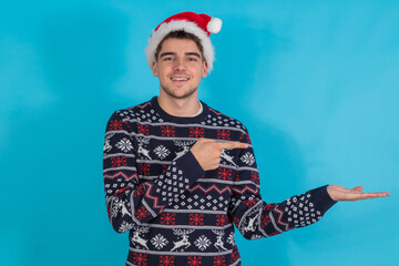 young man with santa claus hat isolated pointing on color background