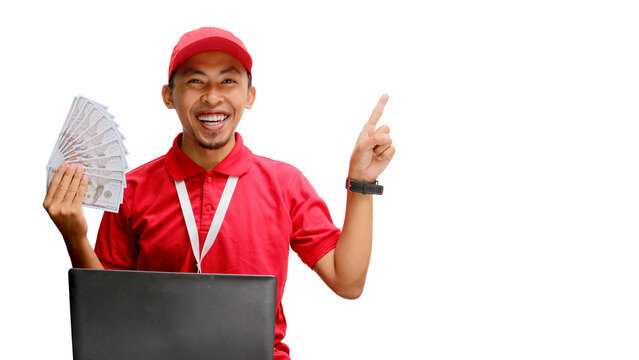 Asian delivery man, holding money while using a laptop against a white background. Concept of professionalism, e-commerce management, financial transactions, delivery services, and business efficiency