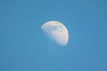 The Moon is in the blue sky on a daytime, close-up view