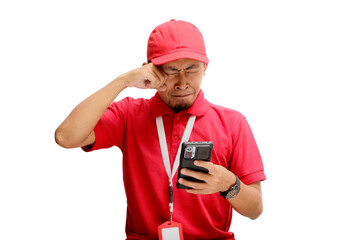 Unhappy Asian delivery man or courier using his phone, feeling sad and frustrated while receiving bad news. Isolated on a white background