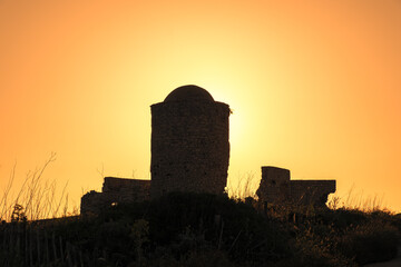 Golden sunrise behind a derelict ancient stone windmill on the cliffs at Bonifacio in Corsica