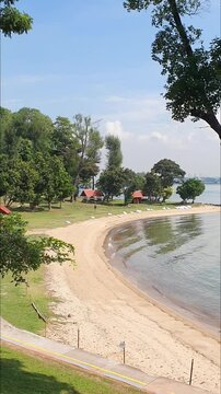 portrait footage of sunny sea view with small pavilions , benches, trees and sandy beach in a tropical island. St John island in Singapore