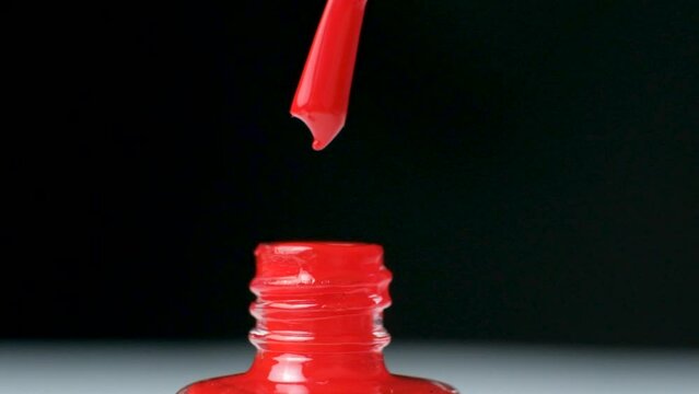 Red nail polish dripping on black background.