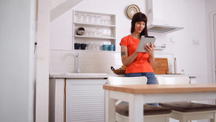 Beautiful, young woman enjoying at home and using her digital tablet
