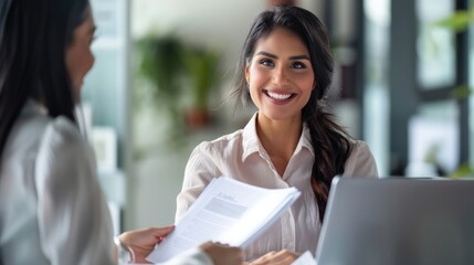 Smiling Native American mid-aged female manager giving documents to a client, showcasing positive business interaction. Mid aged manager successful deal