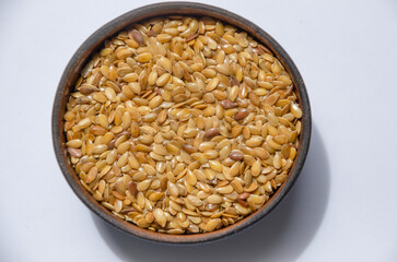 white flax seeds in a wooden round bowl on a light background