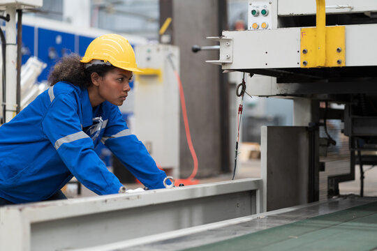 Female engineer inspecting and maintenance CNC machine in factory. Engineer repair machine in line production