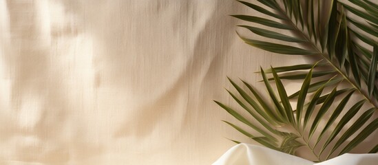 Beige linen fabric serves as backdrop with palm leaf shadows for a summer vacation concept image, offering copy space for text.