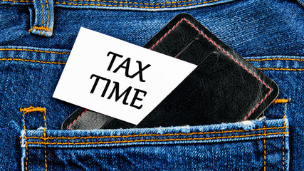 Business and tax concept. TAX TIME on a business card from a black wallet sticking out of a jeans pocket