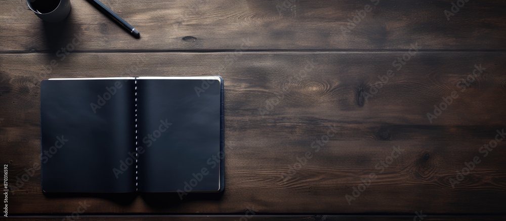Aufkleber Dark desk background with a notebook and pen visible from above, creating a copy space image.